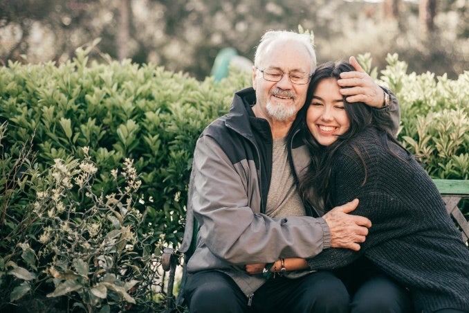 Older adult male and young woman hugging