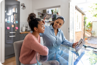 Mom feeling the forehead of her unwell teen with doctor on their tablet