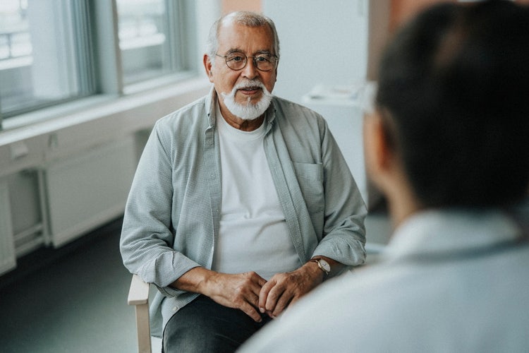 Actor portrayal of older man sitting down talking to a doctor