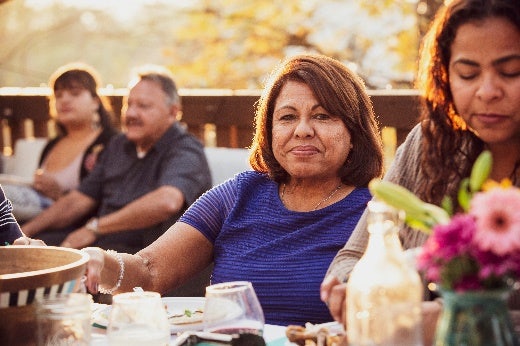 Mom sitting at an outside dinner table with family sitting around her